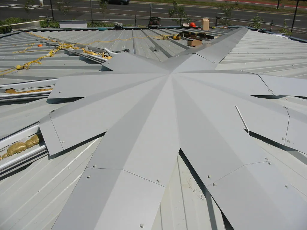 A star-shaped metal flashing being fitted where profiled roof sheets meet at a central point